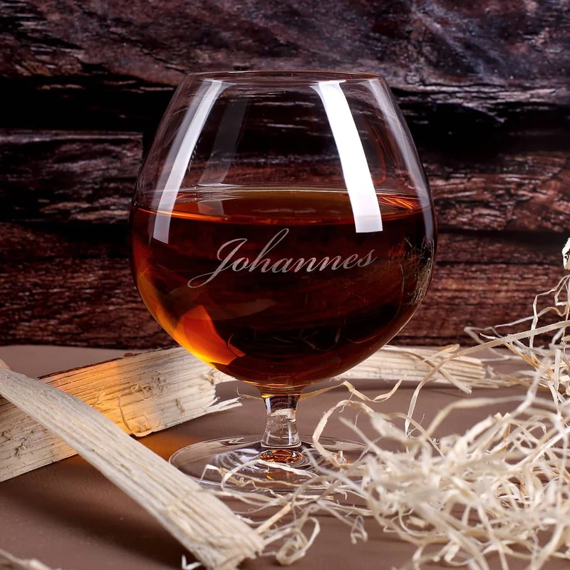 Cognac-Kollektion aus verschiedenen Weinbränden mit Weinbrandglas in gravierter Holzkiste