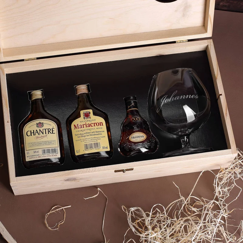 Cognac-Kollektion aus verschiedenen Weinbränden mit Weinbrandglas in gravierter Holzkiste