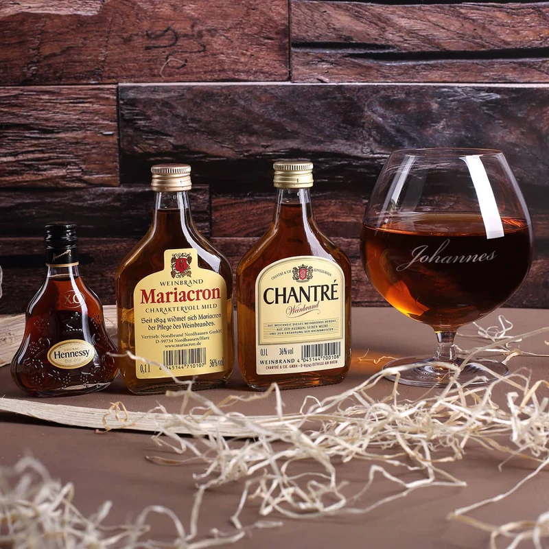 Cognac-Kollektion aus verschiedenen Weinbränden mit Weinbrandglas in gravierter Holzkiste