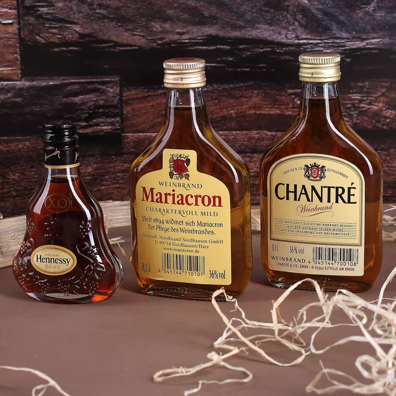 Cognac-Kollektion aus verschiedenen Weinbränden mit Weinbrandglas in gravierter Holzkiste